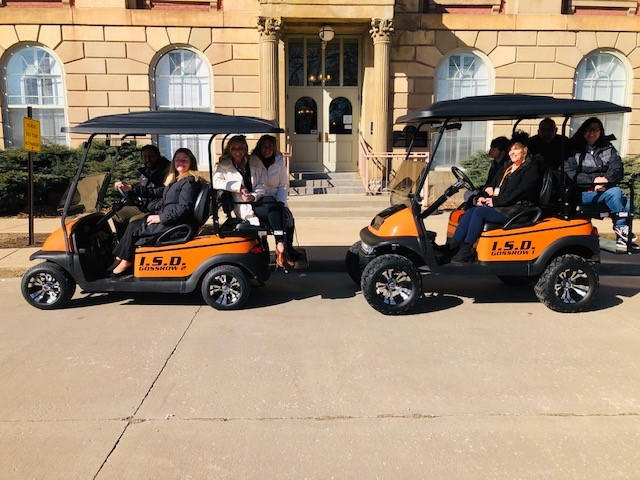 Main Building Admins and the Gossrow family posing with the donated golf carts.